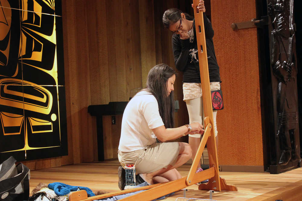Shgen George and daughter Gabby Kay set up a portable weaving loom during the Ravenstail and Chilkat Weavers Symposium at the Walter Soboleff Building's clan house Wednesday.