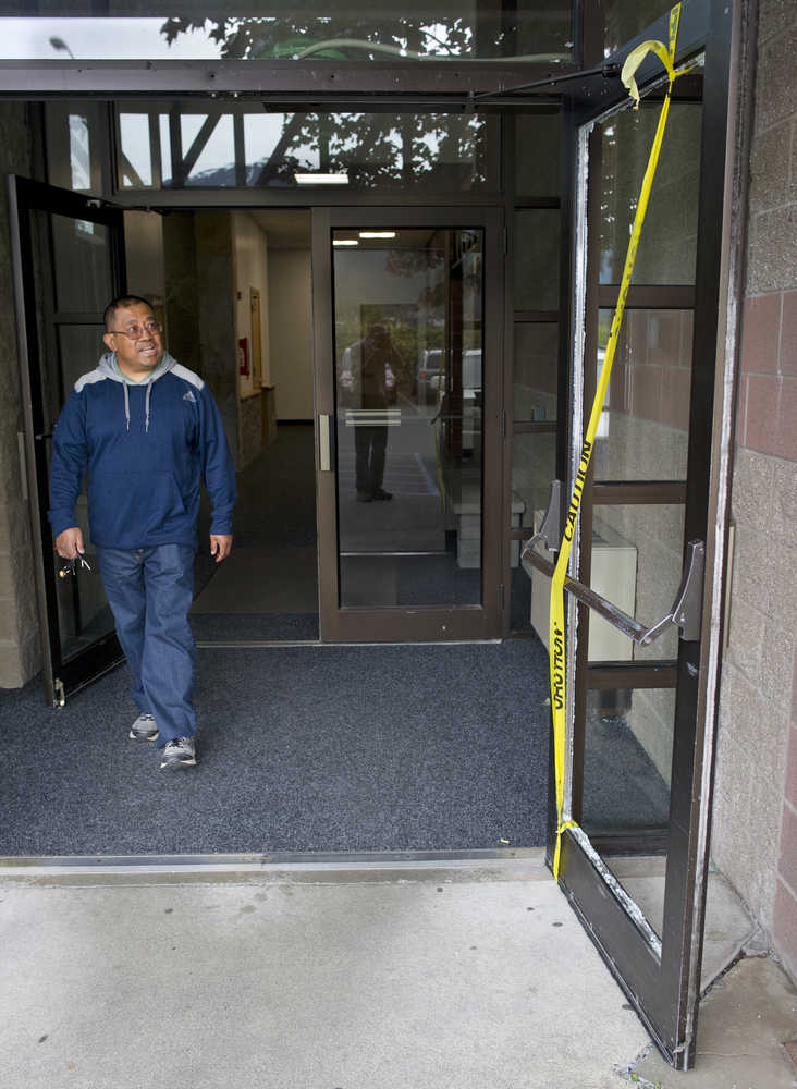 Mauricio Yadao looks at a shattered down at the Foodland Center on Wednesday morning. The building was broken into overnight.