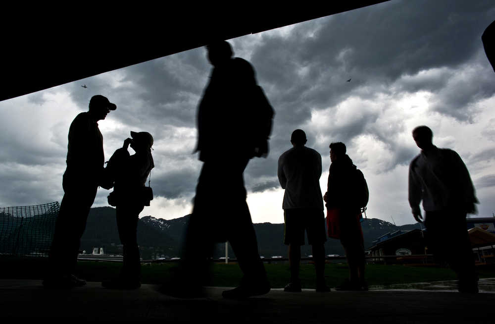 Tourists take shelter under the Marine Park canopy as a rare thunderstorm passes over Juneau in June 2013.