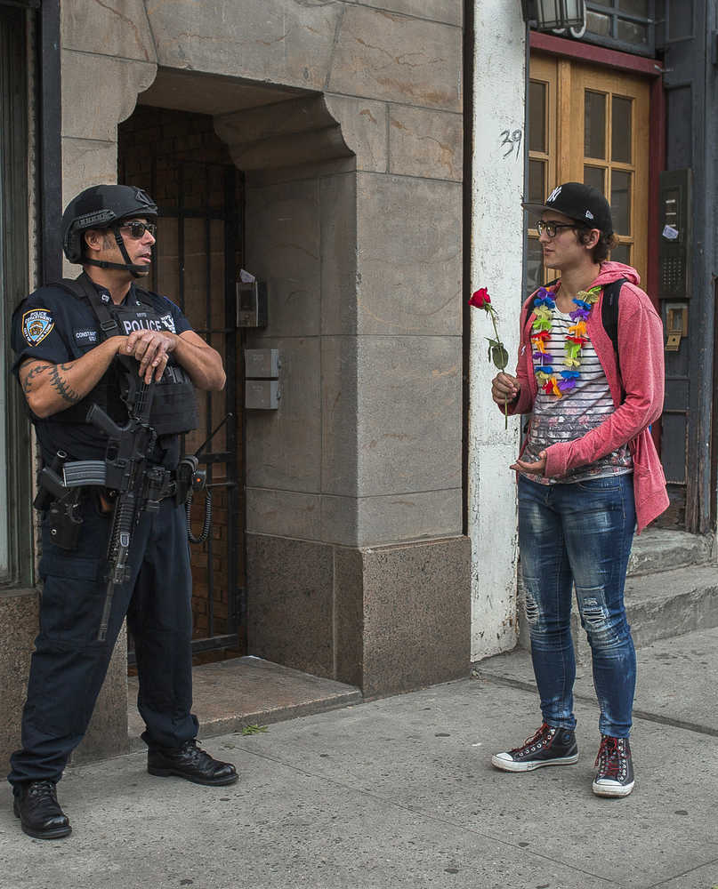 In this June 12 photo, a heavily armed police officer stands guard in New York's Greenwich Village neighborhood as a man arrives to the makeshift memorial near the Stonewall Inn for the victims of the mass shooting in Orlando, Florida.