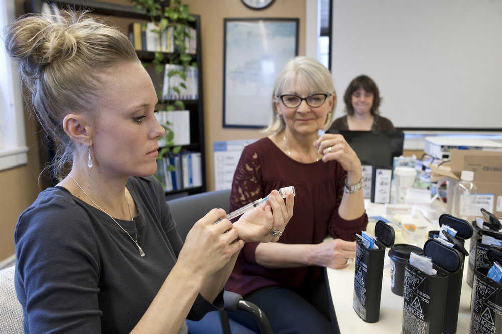 Linda Landvik, center, watches as Chelsi Butler practices drawing Naloxone into a syringe as staff members put together Naloxone kits to be used to prevent deaths from heroin overdoses at the National Council on Alcoholism and Drug Dependence office on Tuesday.