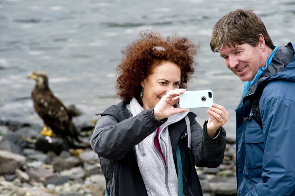 Elsa and Bret Light, of Washington, D.C., take a selfie with a juvenile bald eagle on the shore near the DIPAC Salmon Hatchery on Tuesday.
