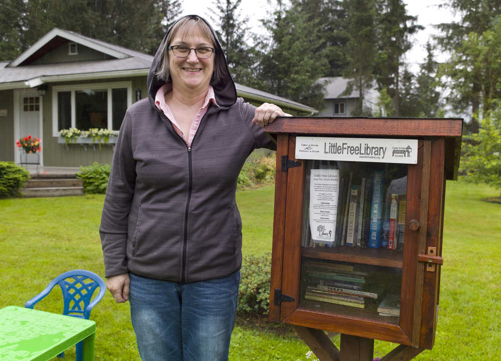 Mary Ann Dlugosch stands next to her Little Free Library set up in her front yard at Radcliffe Court in early July. The library includes a lower shelf that mainly focuses on books for children.