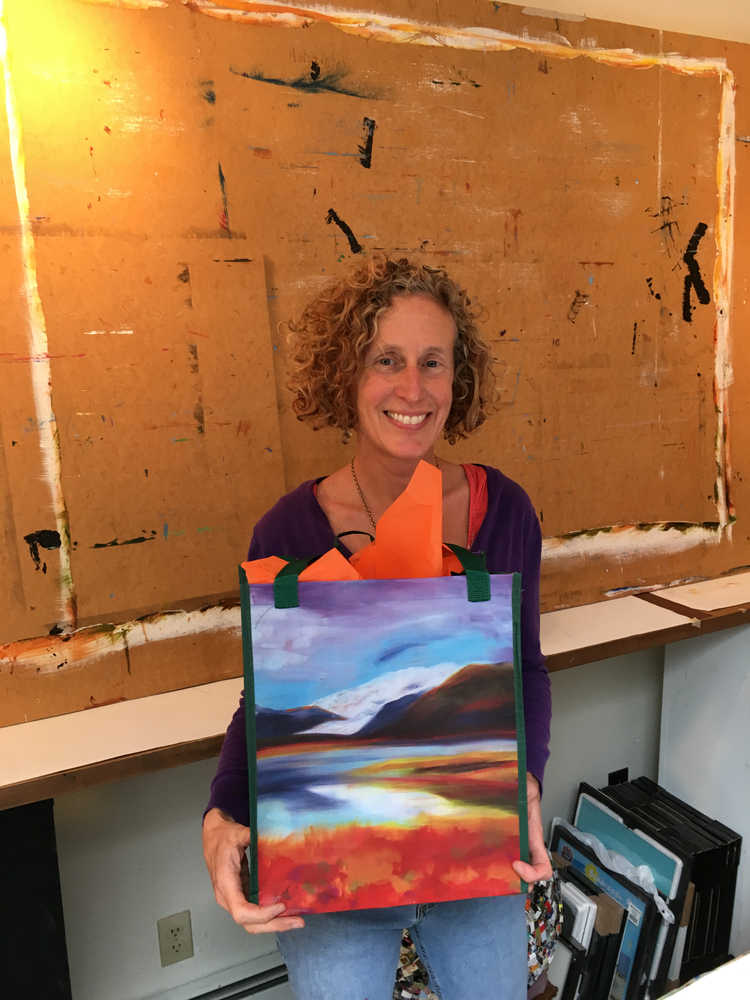 Local Juneau artist MK MacNaughton poses with a tote bag printed with her design "Fall Whispers Good-bye" which won the Resuable Tote Bag Contest.