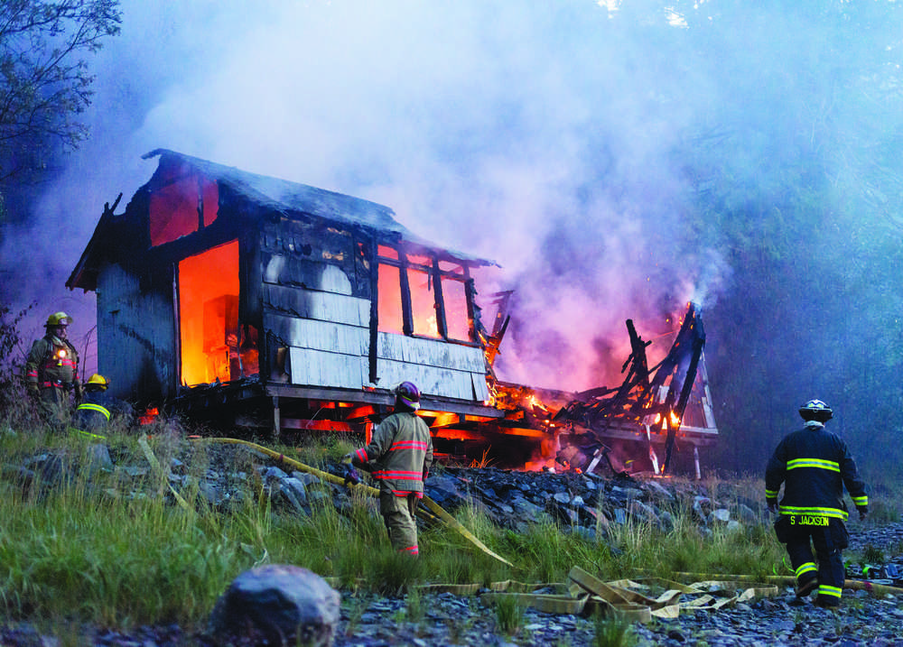 Emergency responders extinguish a house fire on Christopher Road near Knudson Cove Marina on Monday, July 18, 2016.