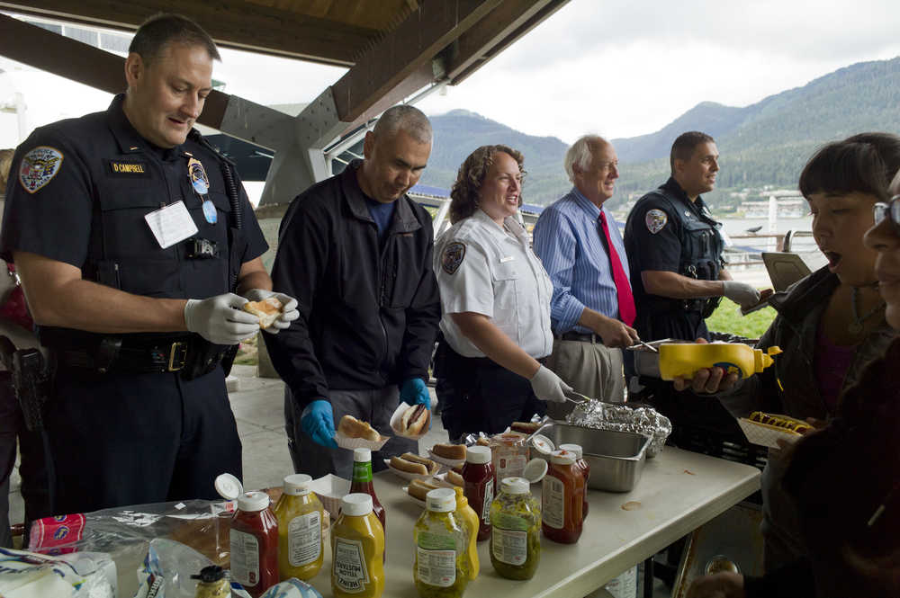 Lt. David Campbell, left, Deputy Chief of Police Ed Mercer, Community Service Officer Sarah Dolan, Mayor Ken Koelsch and Officer Ken Colon serve hot dogs during the Juneau Police Department event for those that want to "be counted as a person against violence, against discrimination, and against hate" at Marine Park on Wednesday.