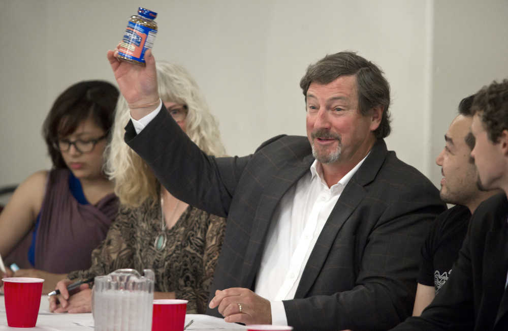 Sandro Lane holds up a container of salmon-oil supplements his company, Alaska Protein Recovery LLC, produces during a panel discussion at the Juneau Chamber of Commerce's weekly luncheon at the Moose Lodge on Thursday. Other business owners on the panel include Lindsey Burnet, of Bustin' Out Boutique, left, Sydney Mitchell, of Shoefly, Rico Worl, of Trickster Company, and Patrick Courtnage, of Adventure Flow, right.