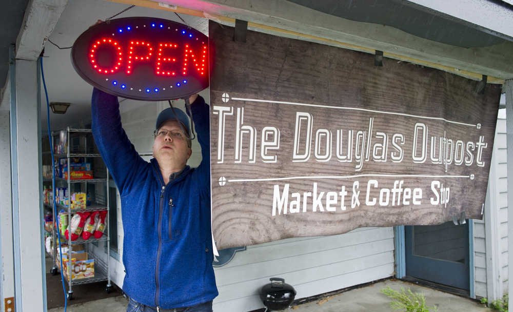 Mark Dundore puts out a neon open sign after rolling out two shelves of goods at his market and coffee stop called The Douglas Outpost on Wednesday. The city is officially keeping Dundore from opening his business inside the building because of a lack of nearby parking spaces required by city code.