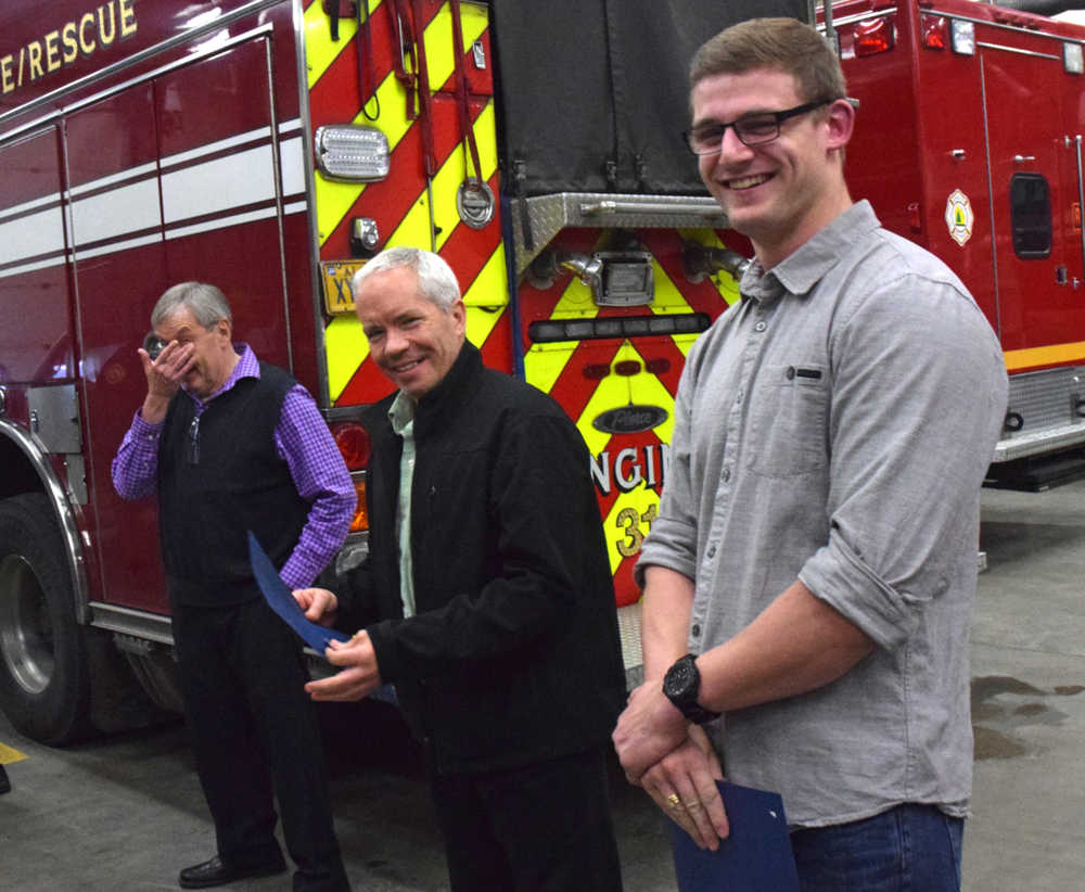 Tommy Vrabec, right, smiles after receiving a life-saving award from Capital City Fire Rescue with Peter Fergin, center, on Friday evening, July 29, 2016 at the Juneau International Airport fire station. At left, wiping tears from his eyes, is Stephen Hamilton, who suffered heart failure but was eventually revived with the assistance of Fergin and Vrabec.