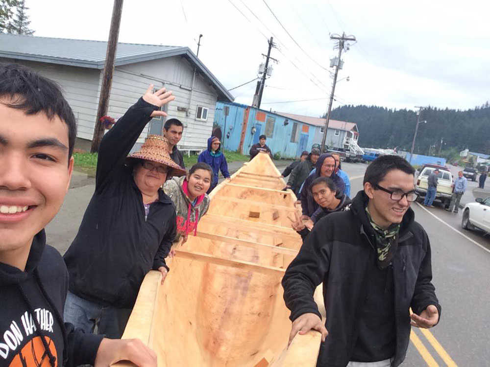 Jerry White, left, takes a selfie with carvers, Hoonah community members, and the newly expanded dugout canoe.