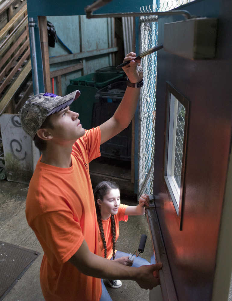 Austin Vargo, left, and Emma Taylor, of the Liberty Bible Church of the Nazarene in Vancouver, Wash., paint an exterior door at The Glory Hole as part of work service trip on Wednesday.