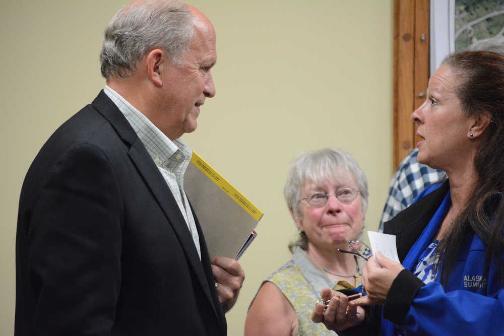 Gov. Bill Walker, left, listens to Homer Mayor Beth Wythe, right, after speaking to the Homer City Council on Tuesday. Homer Advisory Planning Commissioner Roberta Highland, center, looks on.