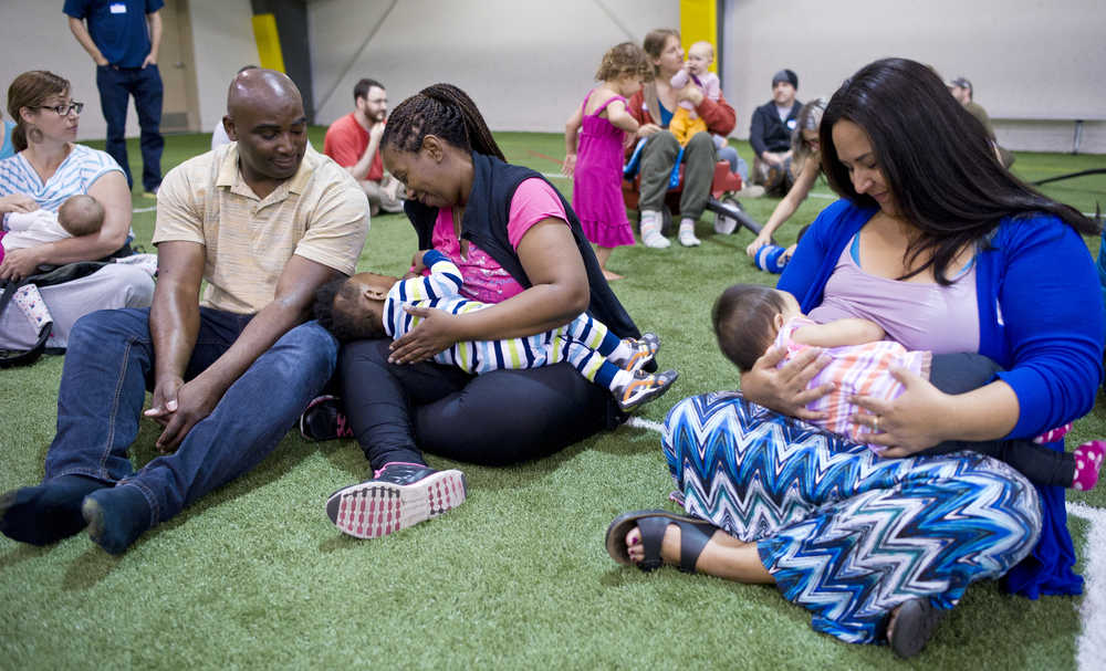 Shakira Vallejo, right, breastfeeds her daughter, Gabriela, 10 months, as Chastity Walker, center, breastfeeds her son, Logan, 16 months, as her husband, Lawnell, watches during the Big Latch On event at Dimond Park Fieldhouse on Saturday.