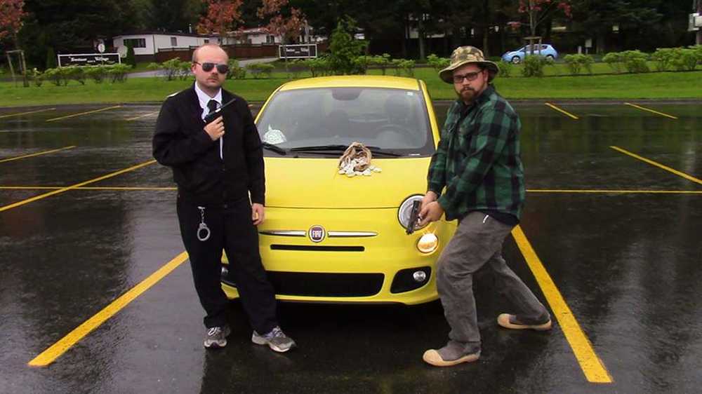 The FBI agent, left, played by Jeremiah Crockroft, and the conspiracy theorist, right, played by Theo Kennedy, pose in front of the FBI agent's yellow Fiat. These two rivals join forces to take down the pelmeni menace in the new film "Pels, Inc." by Danny Peterson.