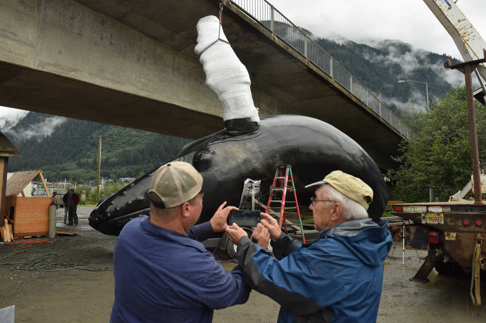Welder Craig Starmer, left, passes his cellphone to sculptor R.T. "Skip" Wallen for a quick photo as Starmer welds the fins on the towering sculpture of a humpback whale that will soon be mounted on Juneau's waterfront. Starmer was joined by crane operator Buck Churchill and assistant Bart Latta for welding work that started Thursday and continued at 7 a.m. Friday.