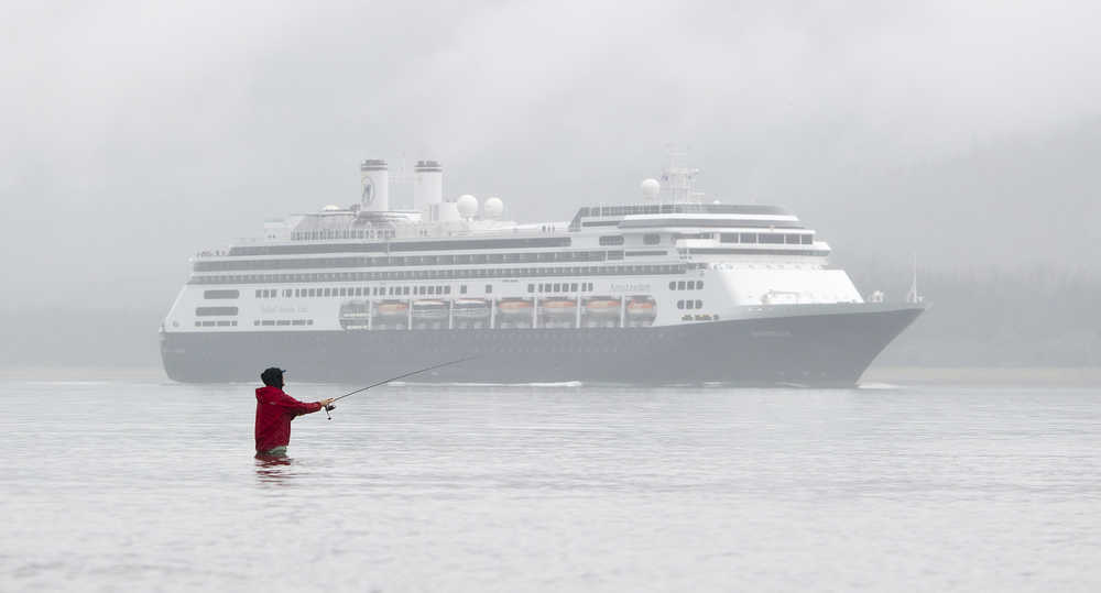 A fisherman casts a lure at the mouth of Sheep Creek as Holland America's Amsterdam arrives in Juneau on Tuesday.