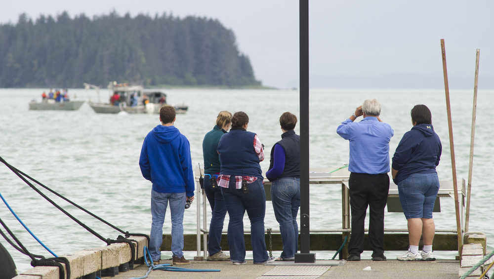 Family members and spectators watch the recovery of Arnold Skeek from the end of the Don D. Statter Memorial Boat Harbor float in Auke Bay on Monday. Skeek, 27, was believed to have fallen off a boat anchored about a half mile outside the harbor on Aug. 14.