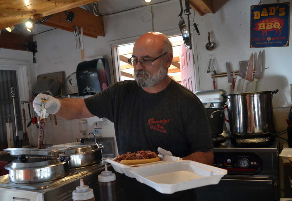 Randy Sutak, owner of Randy's Rib Shack, pours some of his signature barbeque sauce over a pulled pork and briscuit sandwich. Sutak starting perfecting his sauce recipe eight years ago.