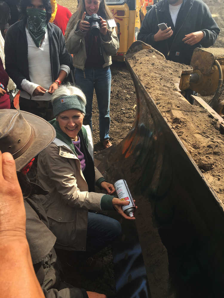 In this Tuesday, Sept. 6, 2016 photo, Green Party presidential candidate Jill Stein prepares to spray-paint "I approve this message" in red paint on the blade of a bulldozer at a protest against the Dakota Access Pipeline in the area of Morton County, N.D. Morton County Sheriff Kyle Kirchmeier said Tuesday that authorities plan to pursue charges against Stein. (Alicia Ewen/KX News via AP)
