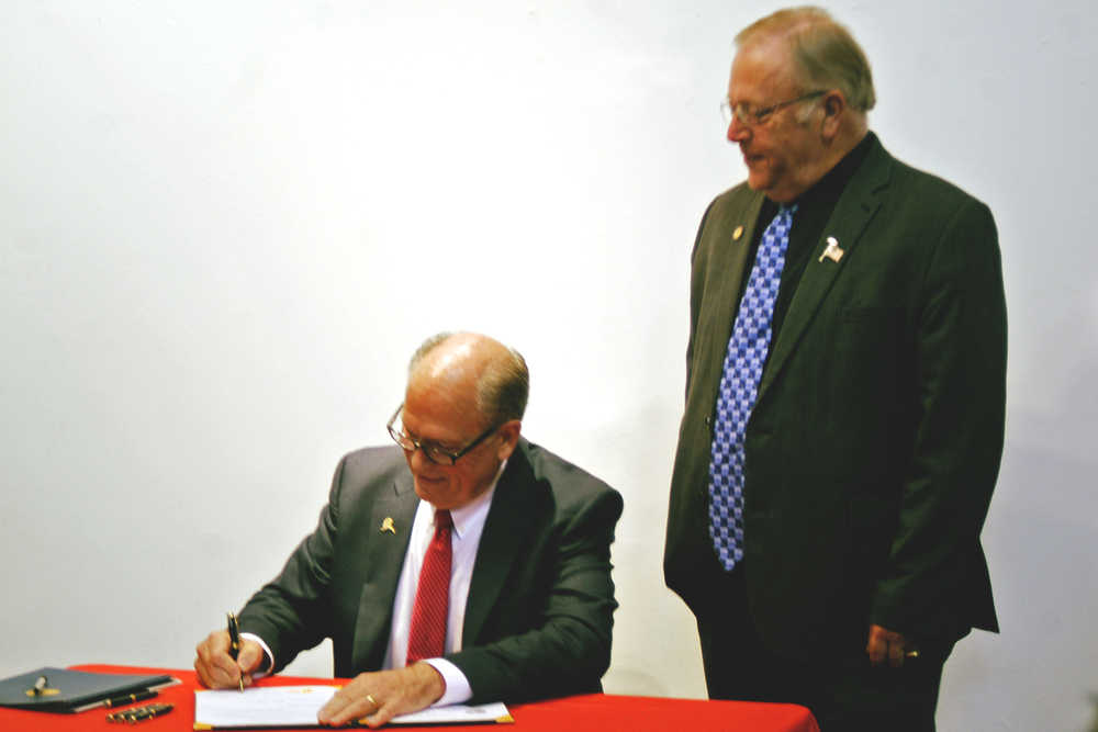 Gov. Bill Walker, left, signs HB 100 into law as Speaker of the Alaska House of Representatives Mike Chenault, right, watches Monday in Kenai. Walker visited the central Kenai Peninsula Monday to give a speech at a joint Kenai and Soldotna chambers of commerce luncheon and to participate in a work session with the Kenai Peninsula Borough Assembly.