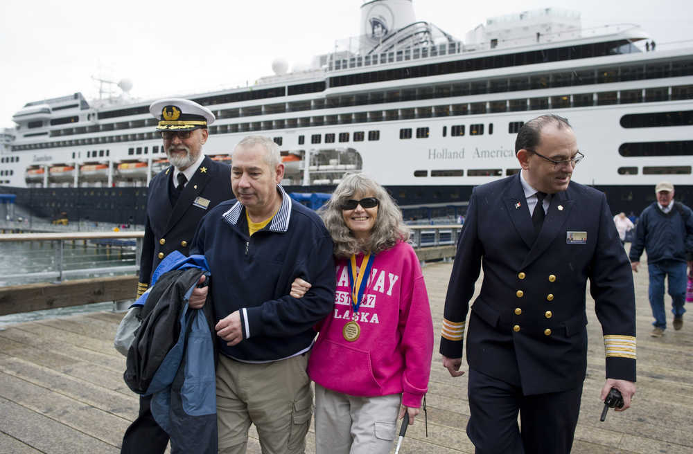 Escorted by Captain PJ van Maurik, left, and Hotel Director Francois Birarda, right, Wendy Yoisten, with her husband John, of St. Albert, Alberta, arrives in Juneau as the one millionth cruise ship passenger for the season in Juneau on Thursday. The Yoisten arrived on the Holland America Line Zaandam.