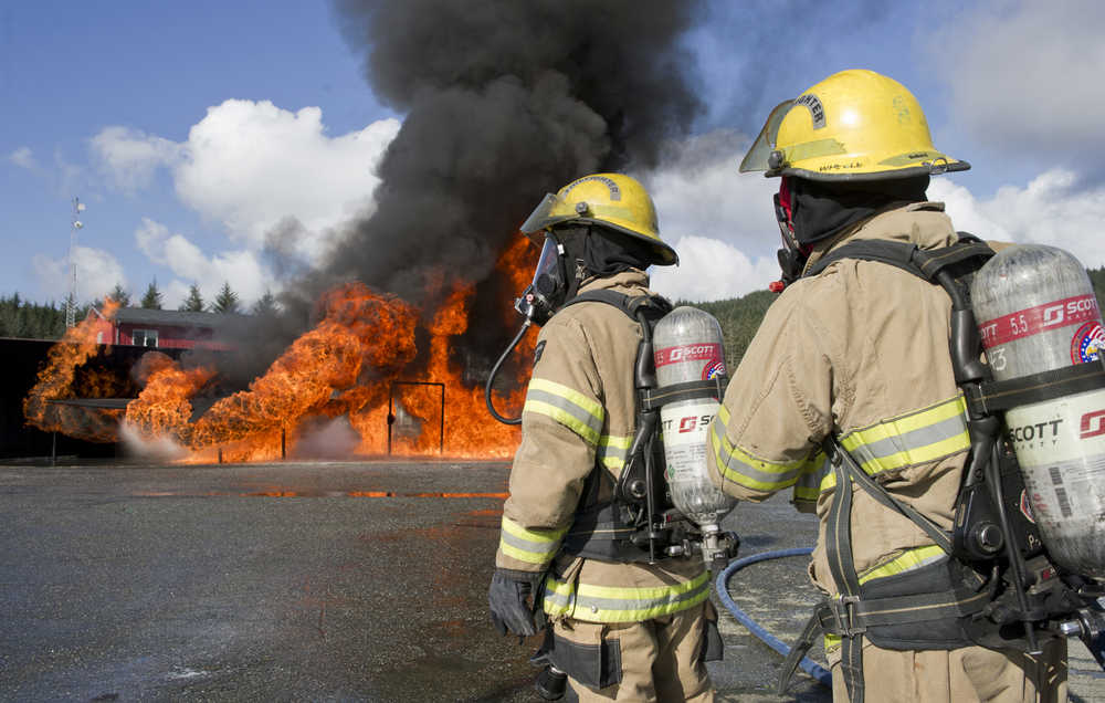 Capital City Fire/Rescue firefighters Cheyenne Sanchez, left, and Andrew Wheeler man a safety hose as they watch a simulated airplane fire at the Hagevig Regional Fire Training Center on Wednesday.