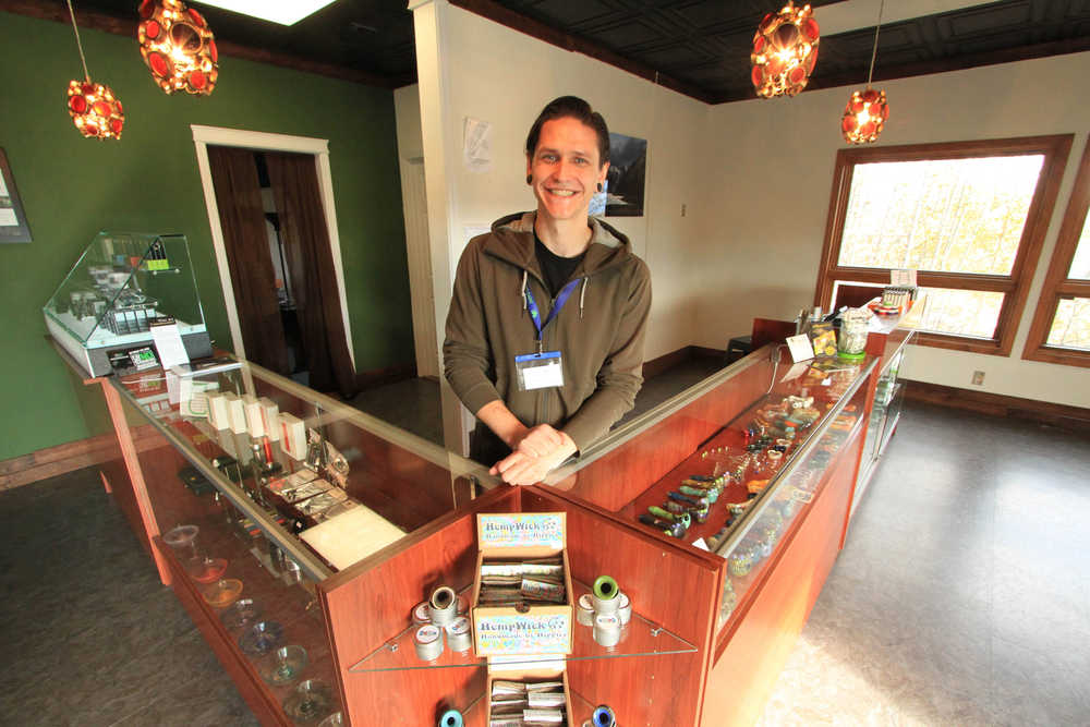 In this Wednesday, Sept. 28, 2016, photo, store owner Caleb Saunders poses for a photo behind the counter of his shop, Green Jar in Wasilla, Alaska. Saunders hopes to sell marijuana from the shop and opposes a ballot measure that would ban sales, cultivation, testing of marijuana in the Matanuska-Susitna Borough. Alaska's fastest-growing municipality will decide Tuesday, Oct. 4, 2016, whether to ban commercial marijuana enterprises. (AP Photo/Dan Joling)