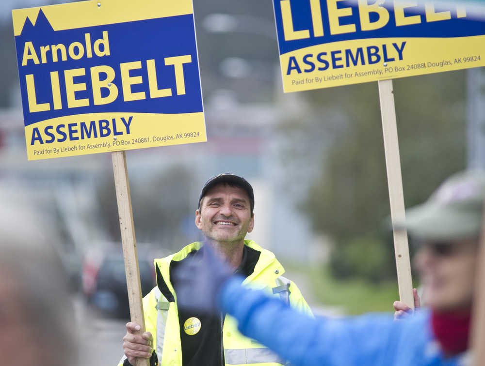 Assembly candidate Arnold Liebelt waves his sign to commuters on their way home at the corner of 10th Street and Egan Drive on the Municipal Election eve on Monday.