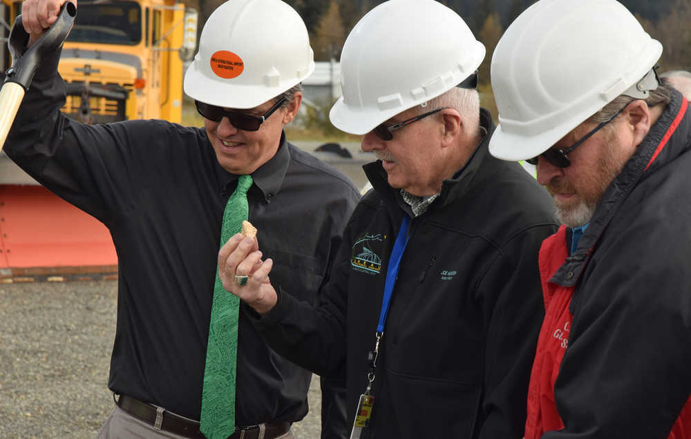Bracketed by city manager Rorie Watt, left, and former Juneau Mayor Merrill Sanford, right, Juneau Airport Board chairman Joe Heueisen examines a ceremonial "gold" nugget given as a souvenir Thursday at the groundbreaking for the new Juneau International Airport Snow Removal Equipment Facility.