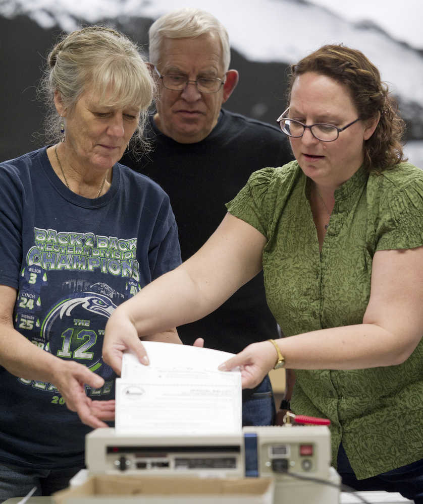 Beth McEwen, municipal deputy clerk, right, instructs Carol and Tom Schriver on running absentee and question ballots through a counting machine in Assembly Chambers on Friday.