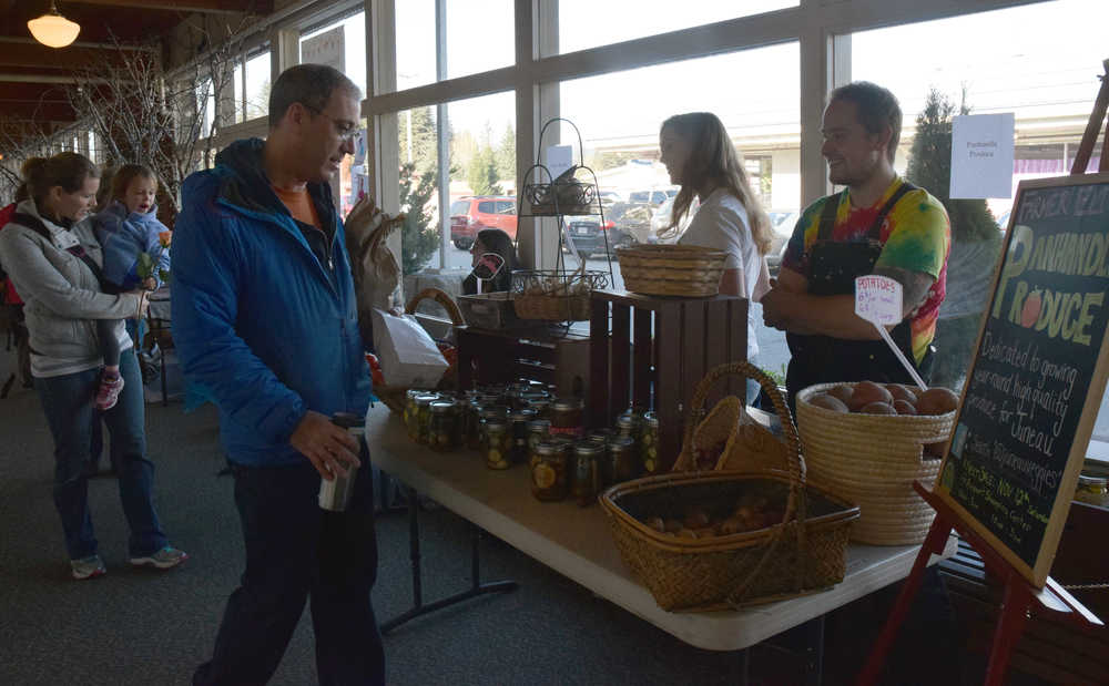 Juneau residents check out Panhandle Produce's display at the Second Saturday Market in the Airport Shopping Center on Saturday morning, and talk with the business' co-owners Eli and Kylie Wray.