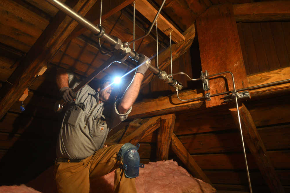 Electrician Richard Cutting of Anchorage's Megawatt Electric tightens a fitting on a 38-millimeter main distribution pipe, part of the Holy Assumption of the Virgin Mary Russian Orthodox Church's new fire suppression system, above the church's sanctuary Thursday, Oct. 6 in Kenai.