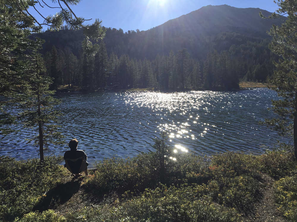 ADVANCE FOR THE WEEKEND OF OCT. 15-16 AND THEREAFTER - In a Sept. 10, 2016 photo, Kathryn Hunter takes in the sunset over Washington Lake northeast of Sun Valley, Idaho, in the White Cloud Mountains.  Washington Lake in the White Clouds, just north of Sun Valley and just south of Stanley,  is a popular hiking location. (Scott McIntosh/Idaho Press Tribune via AP)