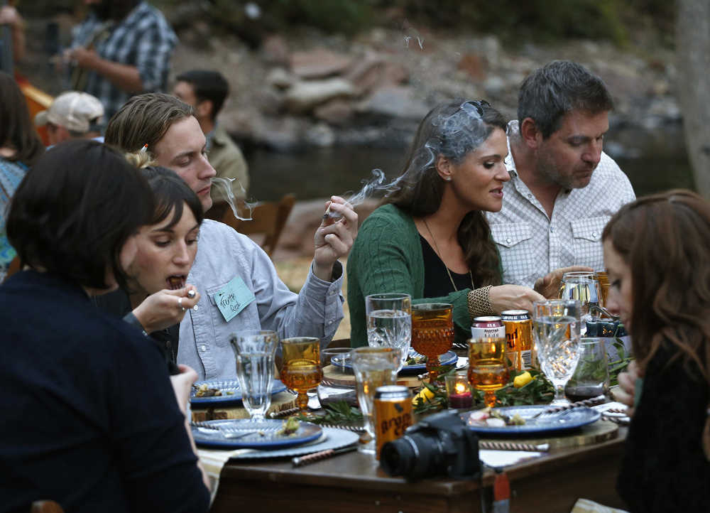 In this Oct. 2, 2016 photo, diners smoke marijuana as they eat dishes prepared by chefs during an evening of pairings of fine food and craft marijuana strains served to invited guests dining at Planet Bluegrass, an outdoor venue in Lyons, Colo. Chefs and pot growers trying to explore fine dining with weed face a legal gauntlet to make pot dinners a reality, even where the drug is legal. (AP Photo/Brennan Linsley)