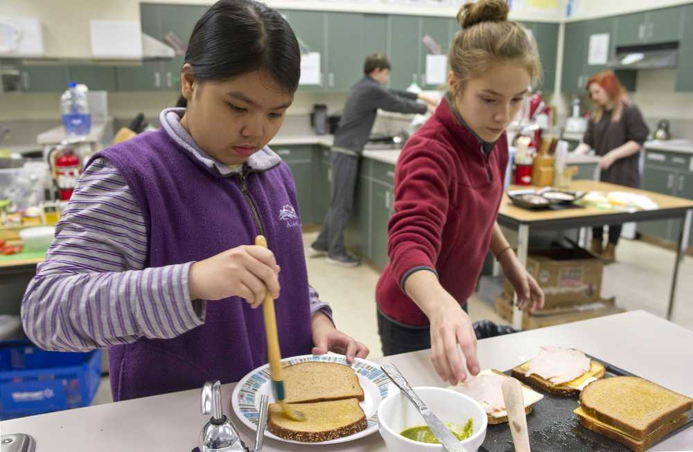 Eighth-graders Joselle Lopez, left, and Luna Ewing work on making their grilled-cheese sandwiches during a Life Skills class at Dzantik'i Heeni Middle School on Thursday.