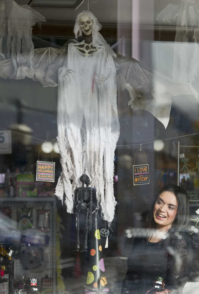 Juneau Drug clerk Brenda Lamas looks out the business' window decorated for Halloween on Monday. The store is one of over 50 downtown businesses welcoming trick-or-treaters on Oct. 31 from 2 to 6 p.m.