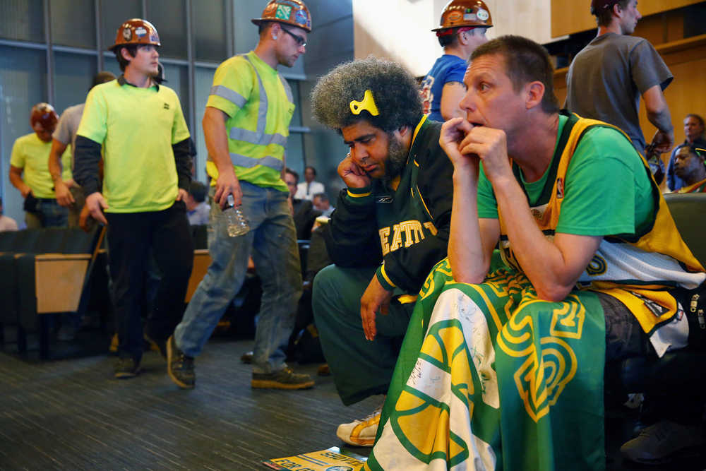 FILE - In this Monday, May 2, 2016 file photo, Seattle SuperSonics fans Kris Brannon, center, and Kenneth Knutsen react to the Seattle City Council's 5-4 no vote against vacating stretch of road where investor Chris Hansen hopes to eventually build an arena that could house an NBA and NHL team. Five women on Seattle's City Council outvoted four men to derail the sports arena project. (Genna Martin/seattlepi.com via AP)