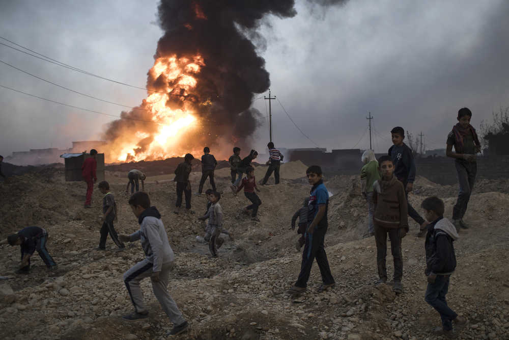 Children play next to a burning oil field in Qayara, south of Mosul, Iraq, Thursday, Nov. 3, 2016. A senior military commander says more than 5,000 civilians have been evacuated from newly-retaken eastern parts of the Islamic State group-held city of Mosul and taken to camps.  (AP Photo/Felipe Dana)