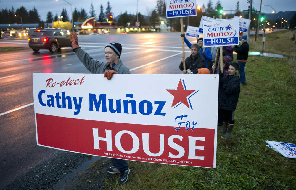 Juan Muñoz waves a large sign for his wife, Rep. Cathy Muñoz, during the evening commute on the eve of the national and state elections Nov. 7, 2016.