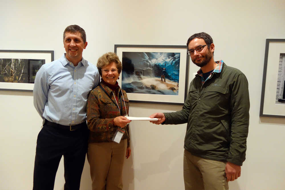 Juneau photographer Chris Miller, right, receives his prize for his Juror's Choice Award photo, "Mendenhall Moulin," center, from MaryLou Gerbi, the vice president of Friends of the State Library, Archives and Museum and Addison Field, chief curator of the Alaska State Museum on Nov. 4.