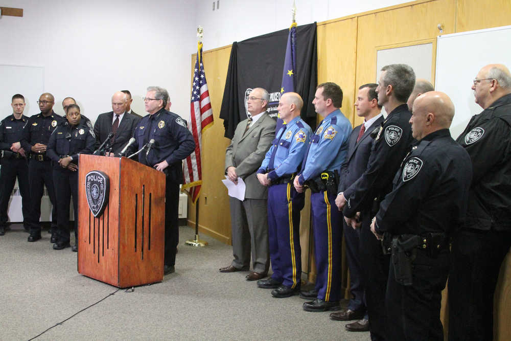 Anchorage Police Chief Chris Tolley, surrounded by Alaska law enforcement officers, speaks at a news conference in Anchorage on Tuesday. Tolley said the gun used in the shooting of an officer over the weekend has been linked to five killings in Alaska's biggest city this year.