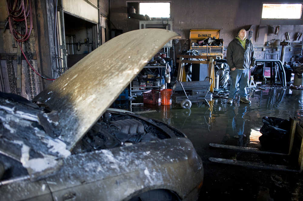 Automotive business owner Carson Knight takes stock inside his automotive shop on Thursday after a late night fire destroyed a number of businesses in the building located behind the Sandbar on Industrial Boulevard.
