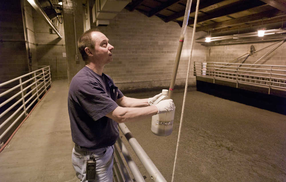 Mendenhall Wastewater Treatment Plant operator Dave Miller takes a water sample from one of the plant's eight treatment tanks on Wednesday. Excess oil and grease causes a heavy foam to form in the tanks.