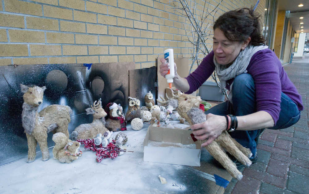 Sherri McDonald decorates animals she made for REACH's annual Christmas window outside their Third Street offices on Friday.