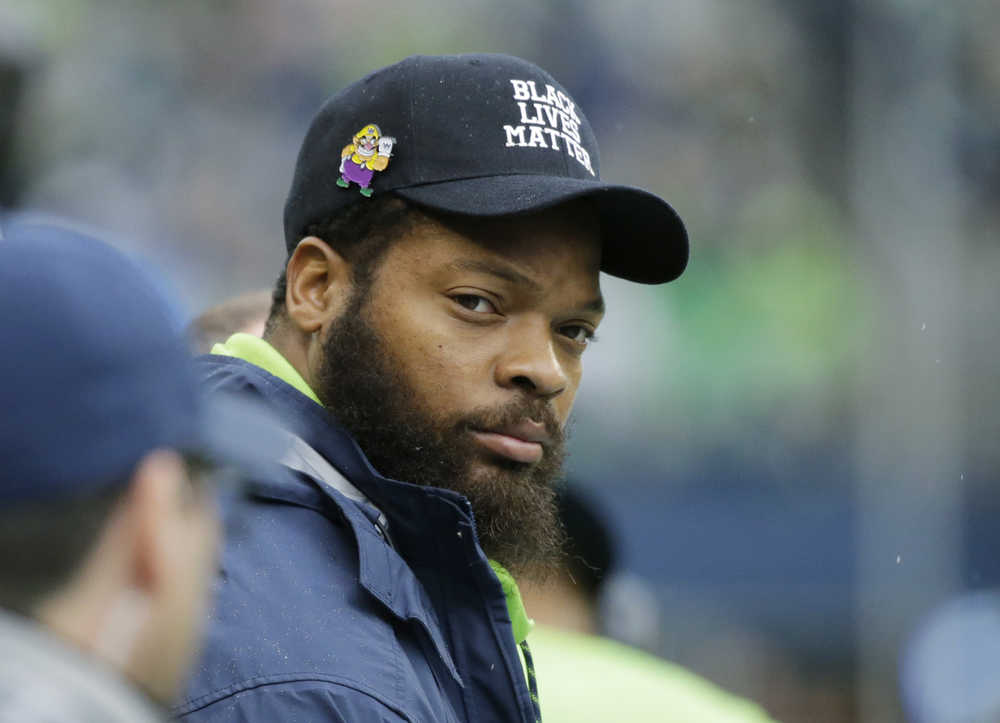 Seattle Seahawks injured defensive end Michael Bennett wears a hat that reads "Black Lives Matter" as he sits on the sideline during an NFL football game against the Philadelphia Eagles, Sunday, Nov. 20, 2016, in Seattle. (AP Photo/John Froschauer)