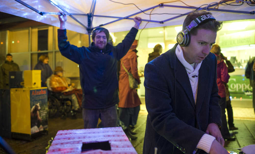 Carl Liberty keeps the winds from blowing away a portable rain shelter at Manuel Hernandez, aka DJ Manu, keeps the music going on Front Street during Gallery Walk on Friday, Dec. 2, 2016.