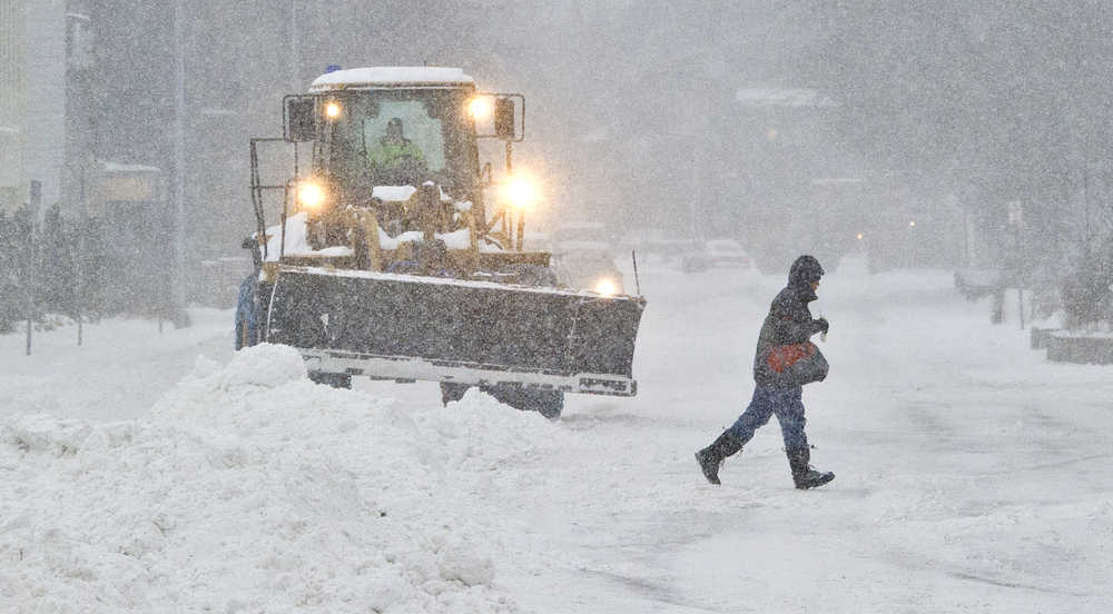 A pedestrian crosses Glacier Avenue as a city vehicle moves snow on Wednesday, Dec. 7, 2018.