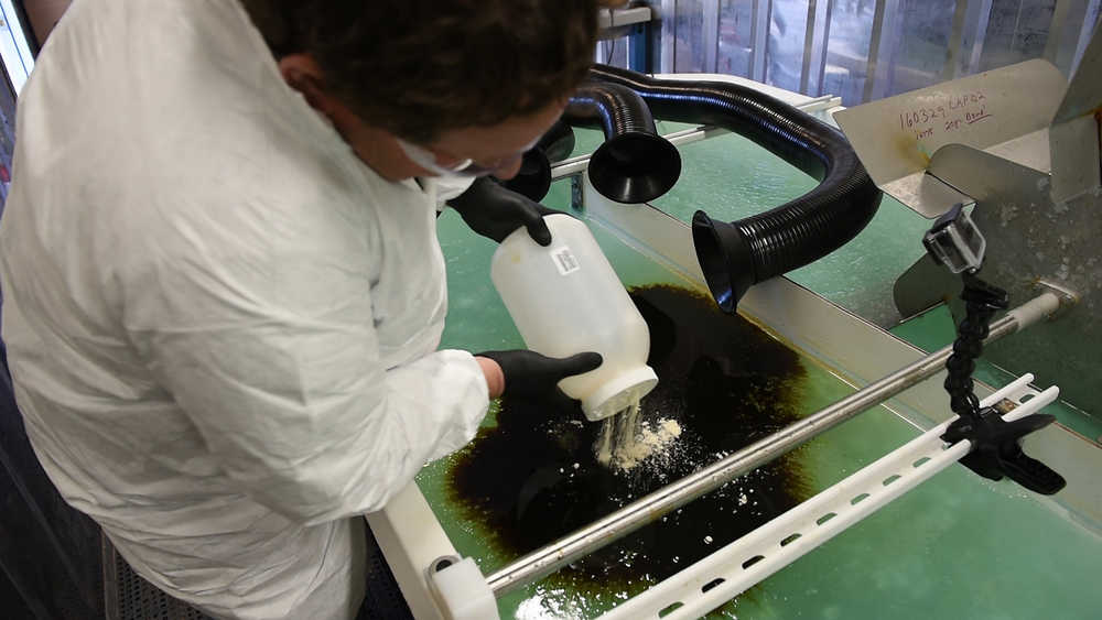 In this Dec. 9 photo, Pacific Northwest National Laboratory microbiologist Robert Jeters sprinkles PNNL's chemically modified sawdust onto a small oil spill inside the Arctic simulation lab, where researchers mimic extreme freezing conditions and make icy slush that is similar to what is found on the surface of the Arctic Sea.