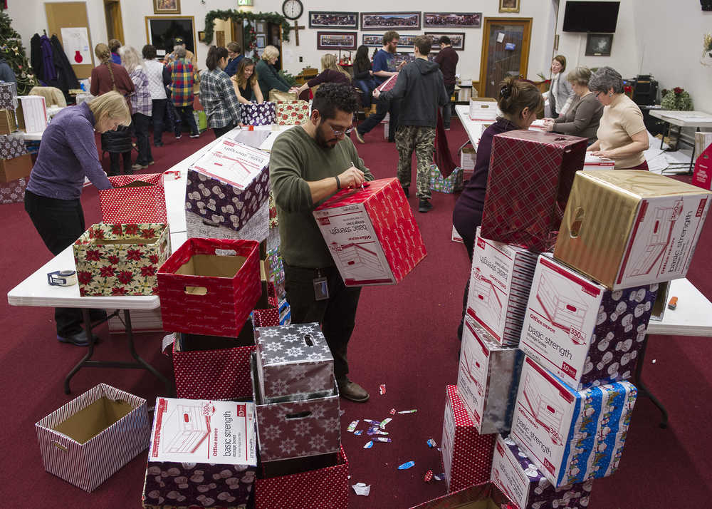 Enrique Sanchez decorates boxes with Rotary members and local real estate agents as part of the Racheal MacLeod Christmas Dinner Box Project at The Salvation Army Church on Monday, Dec. 19, 2016. The boxes, which will contain all the ingredients for a holiday dinner, will be available Thursday and Friday to 360 local families. The project is coordinated by the three Rotary clubs and the Rotaract club of Juneau.