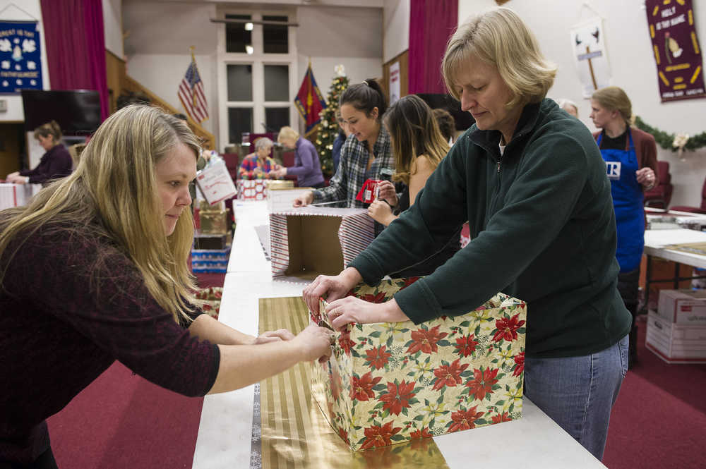 Rotary members Leah Van Kirk, left, and Amy Lujan wrap boxes with others as part of the Racheal MacLeod Christmas Dinner Box Project at The Salvation Army Church on Monday, Dec. 19, 2016. The boxes, which will contain all the ingredients for a holiday dinner, will be available Thursday and Friday to 360 local families. The project is coordinated by the three Rotary clubs and the Rotaract club of Juneau.